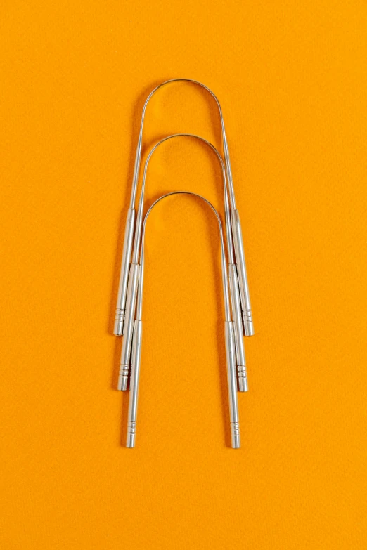 a couple of metal hair clips sitting on top of a orange surface