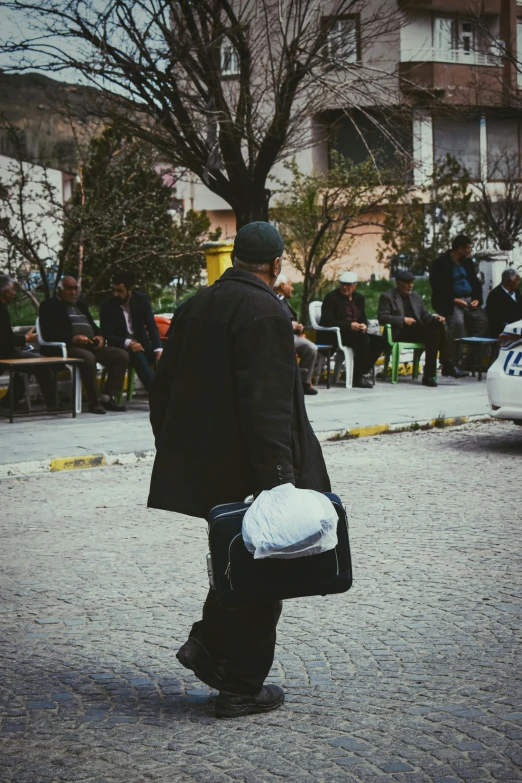 the man is walking along the street with his back towards the car