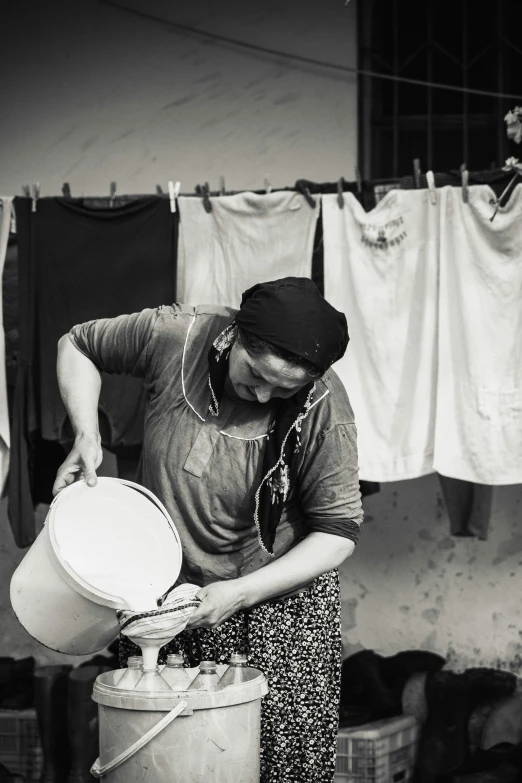 a black and white image of a woman washing clothes