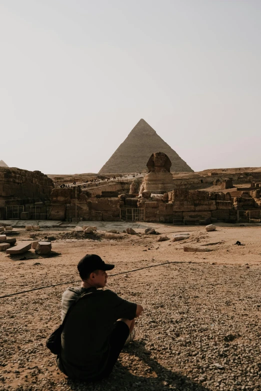 a young man is sitting on the ground in front of some building