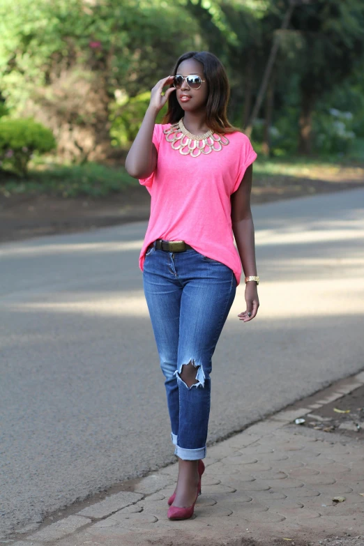 a young woman walking down the sidewalk wearing pink top