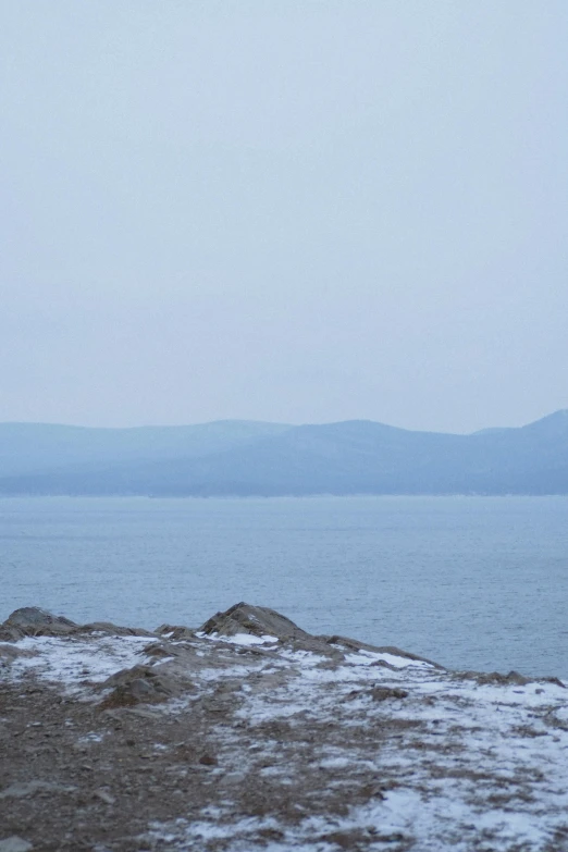 a person stands on top of a snowy mountain near the water