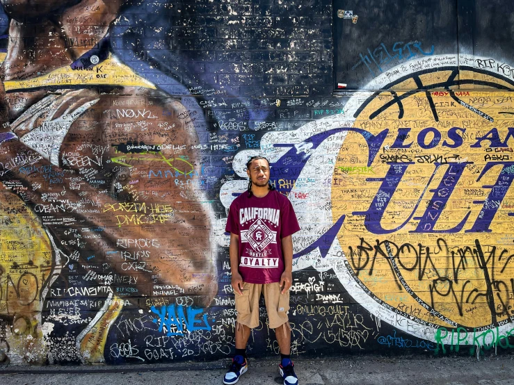 a boy poses for a pograph in front of graffiti wall