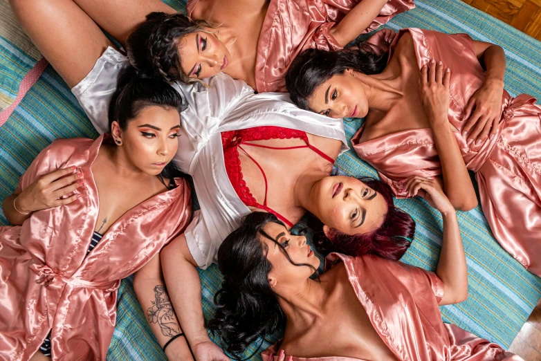 six  women laying on a bed posing