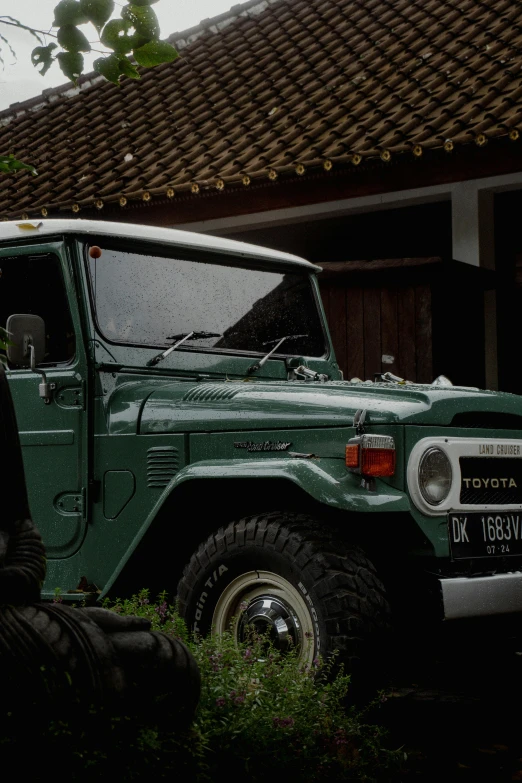 a green jeep parked in front of a brick building