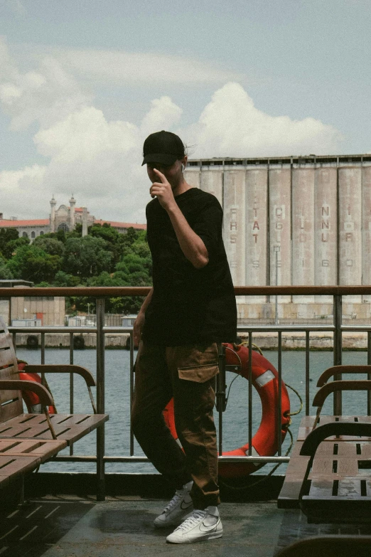 a young man is talking on his cell phone by the water