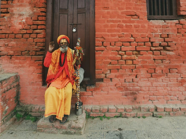 a man dressed in orange sitting near a building