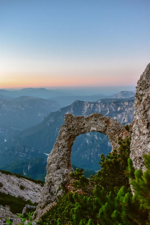 an arched rock arch in the middle of a mountain valley