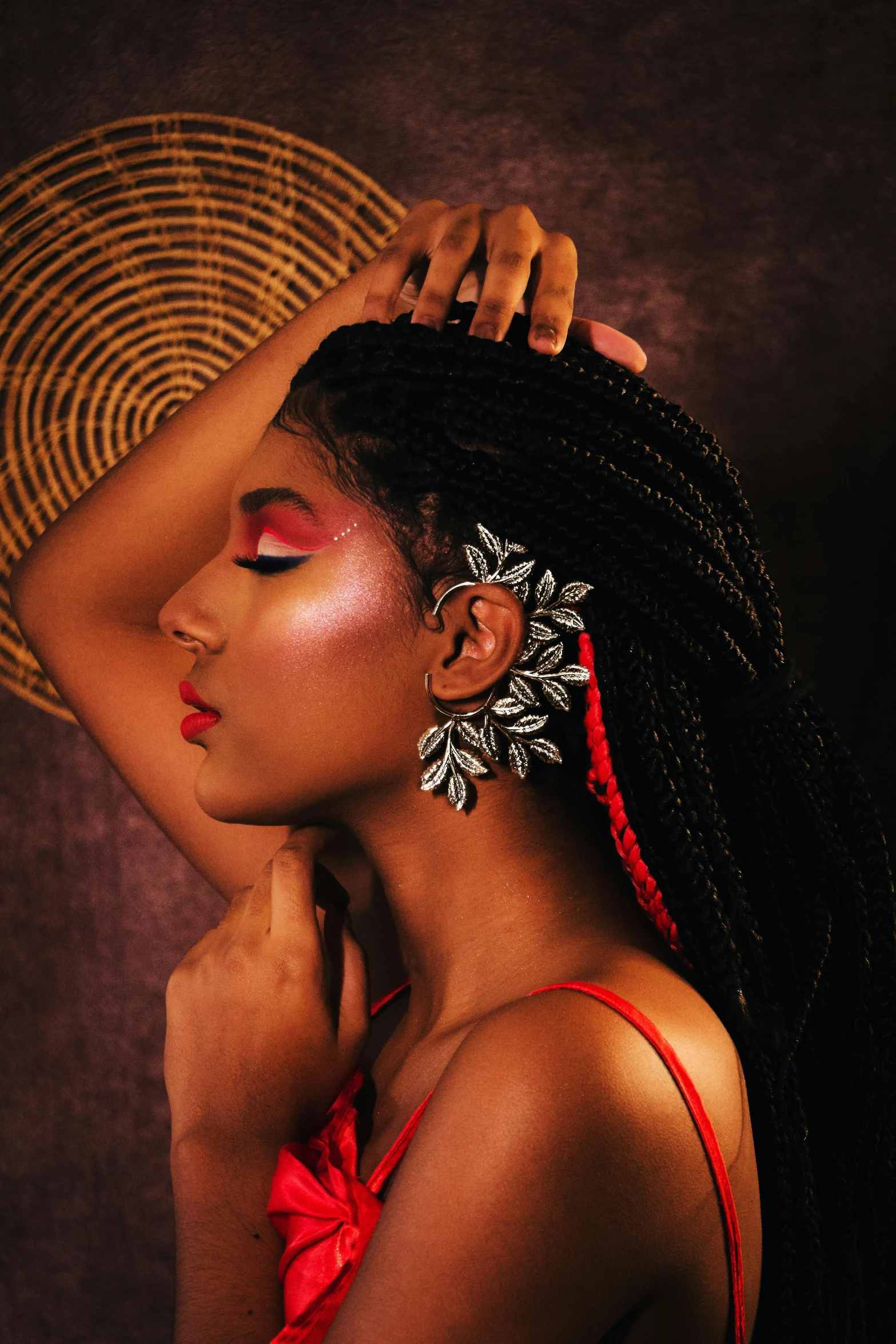 a woman with long hair and big earrings standing next to a hat