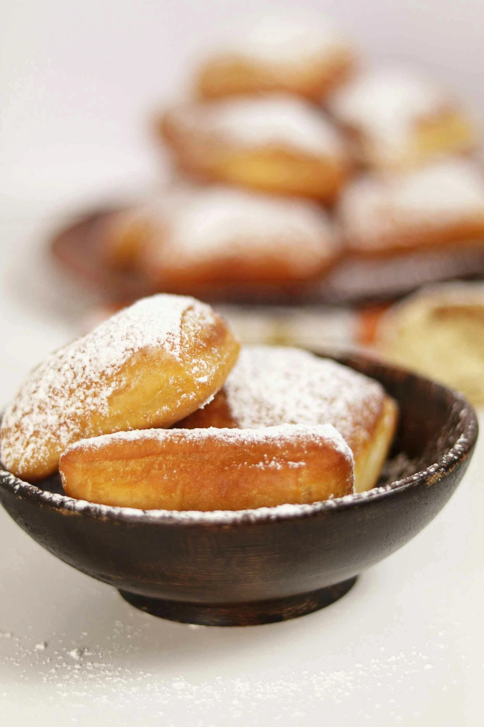 some sugar coated doughnuts in a small black bowl