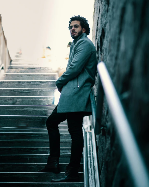 a man in long coat posing at top of steps