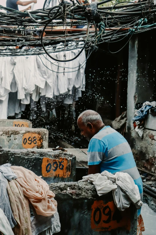 an older man is washing his clothes in the street