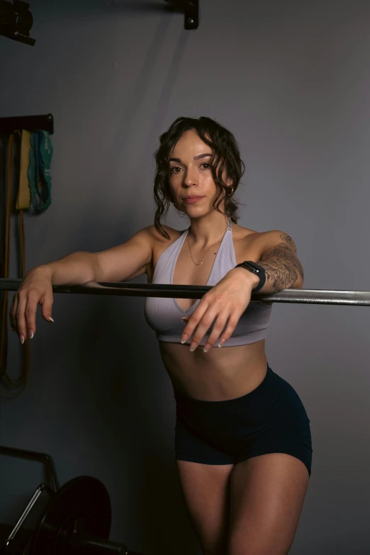 an attractive woman in a gym  and tights holding a bar