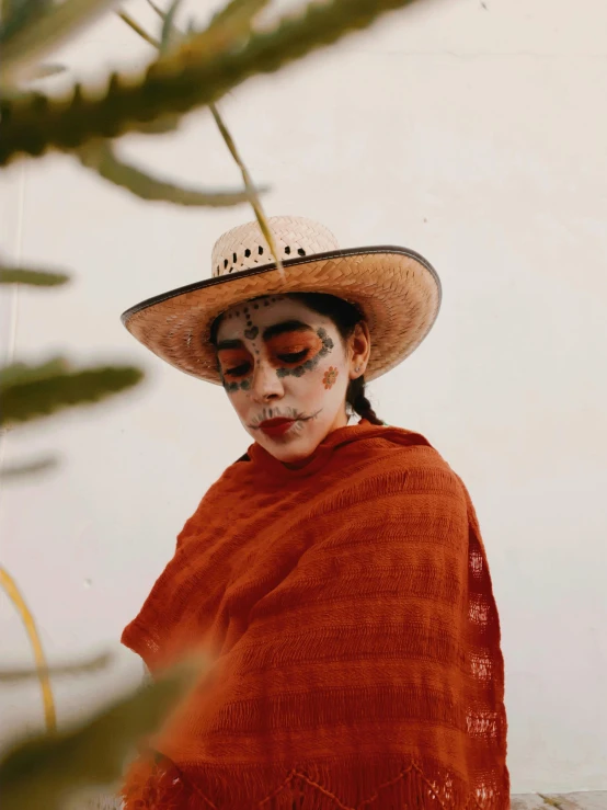 woman in orange outfit wearing sombrero and white face paint
