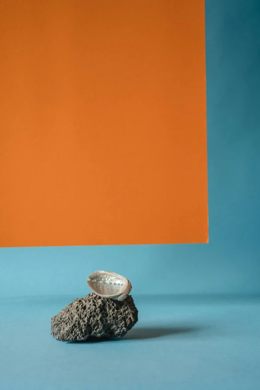 a small ceramic rock sits in front of an orange backdrop