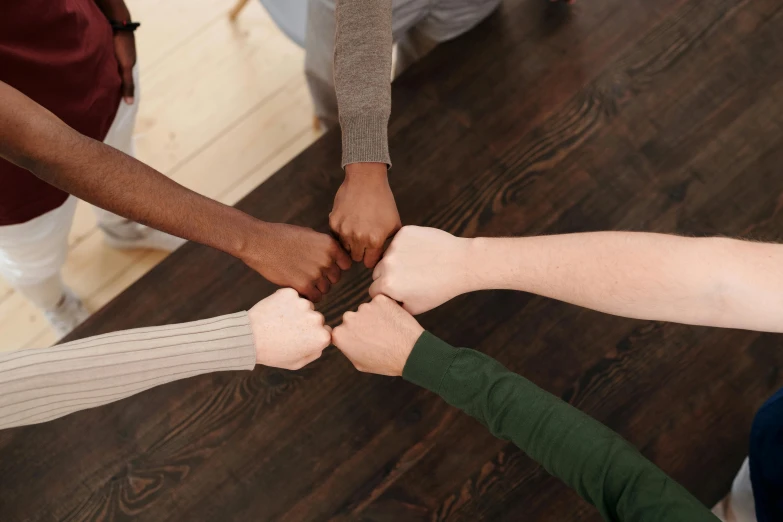 six friends putting their hands on top of each other together