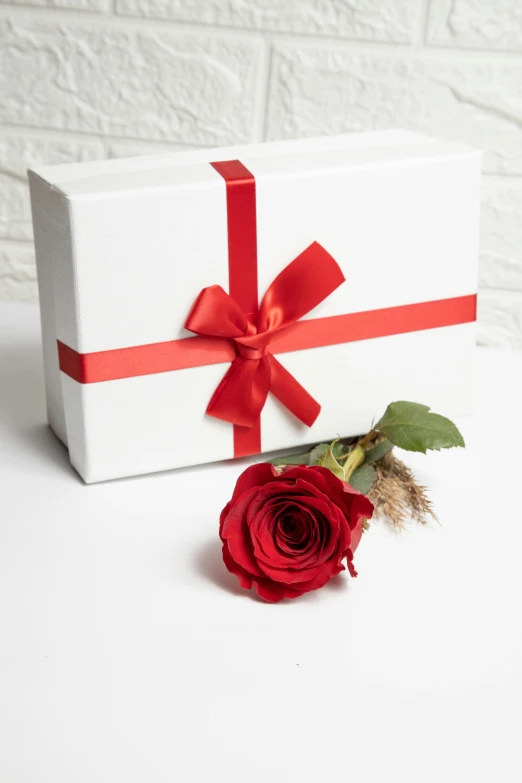 a single rose is placed next to a wrapped gift