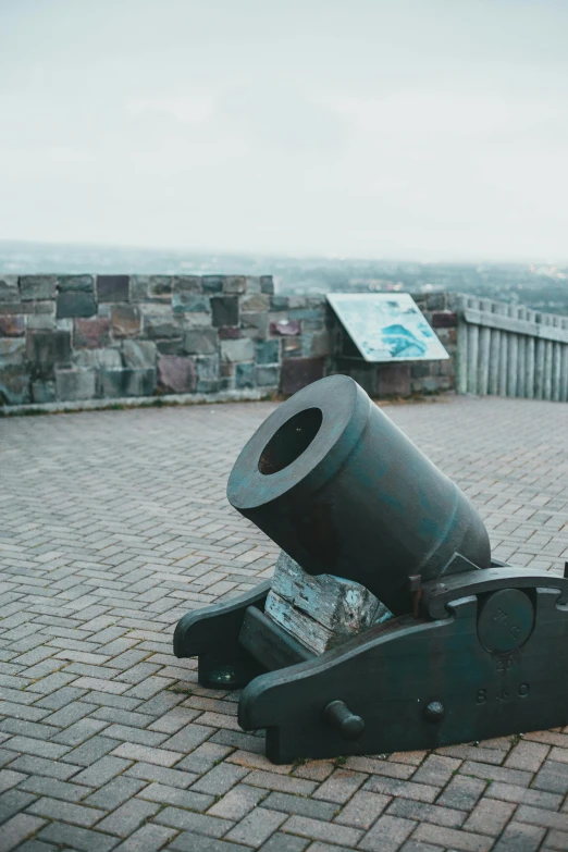 a cannon is placed on a brick area with a stone wall behind it