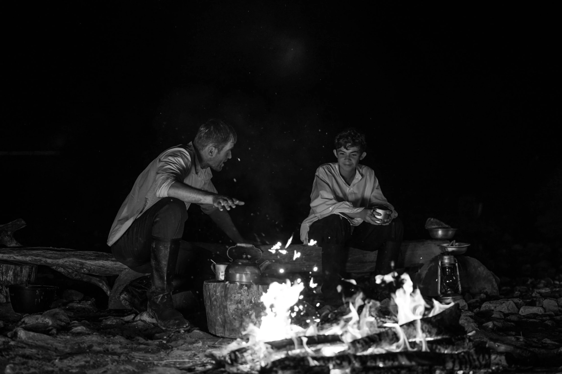 two people sitting around a camp fire