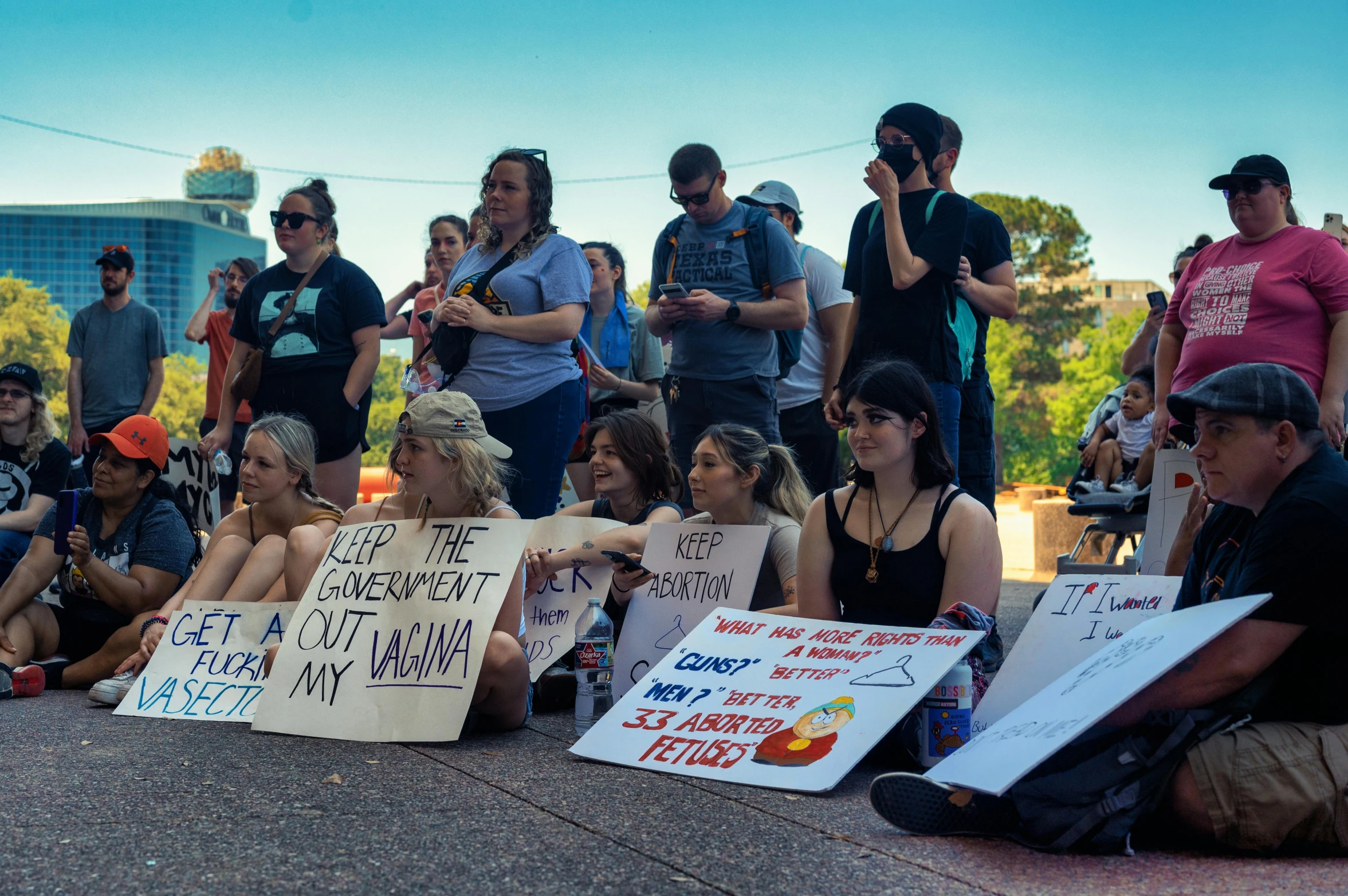 a group of people sitting on the ground with signs