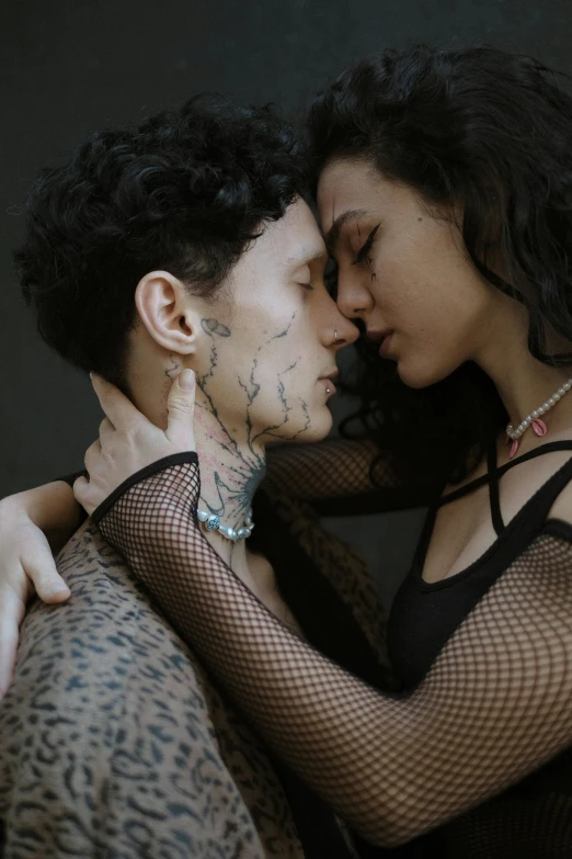 a couple hugging in a black dress with tattoos on the face