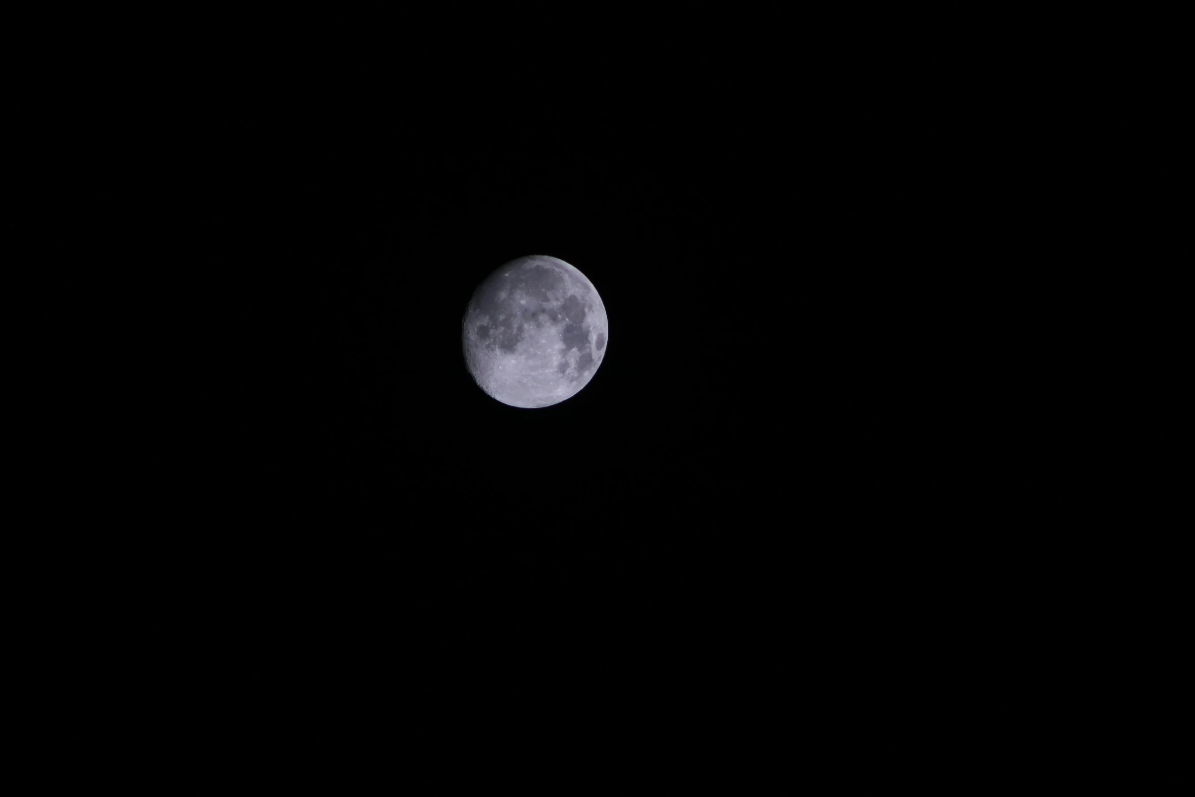 a full moon is seen through the black sky