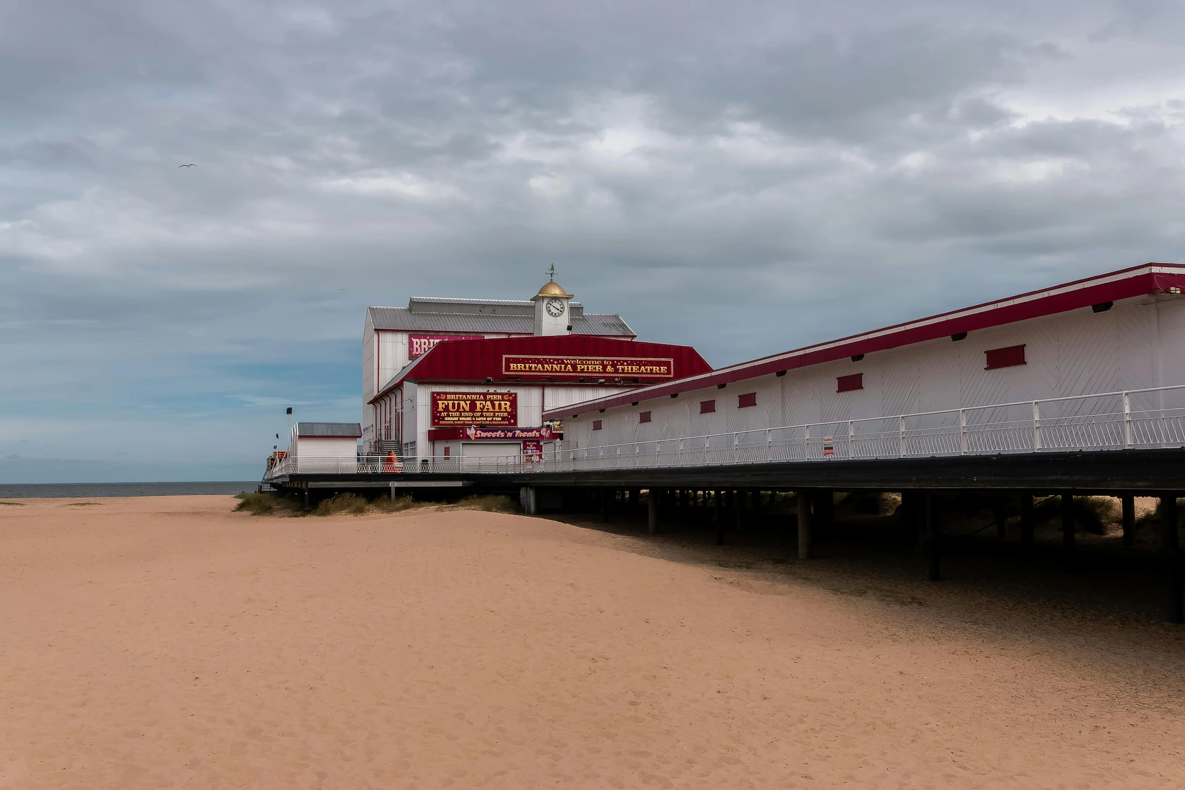 a beach has a dock on the sand and buildings