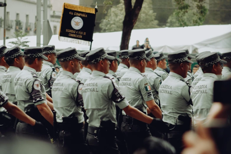 uniformed men stand side by side in front of a banner