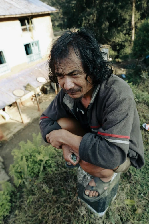 a man with long hair is sitting on a fire hydrant