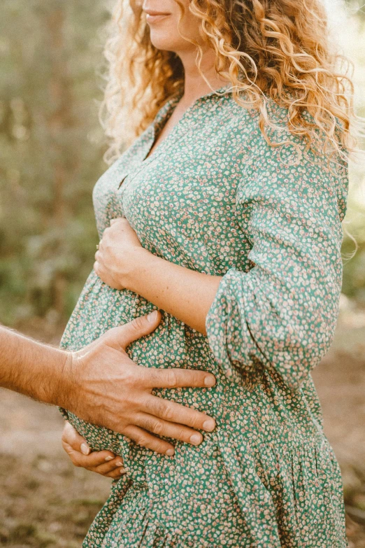 a young woman is in a park with her baby bumping on her pregnant belly