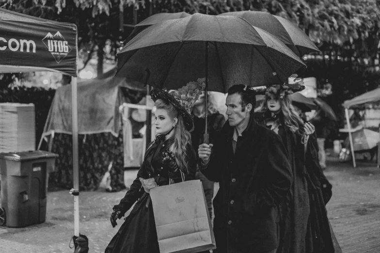 three women under an umbrella walk down the street