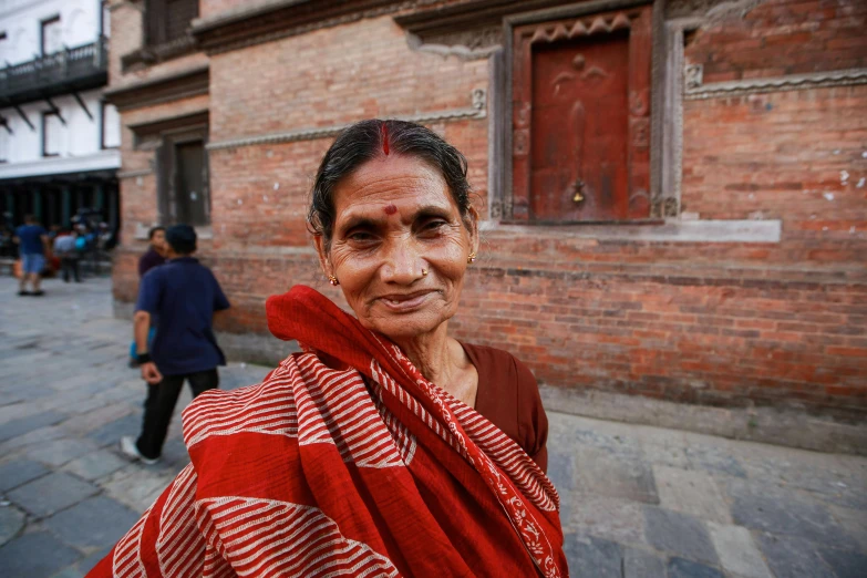 a women wearing a red sari is in an old, quaint alley