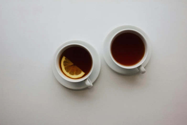 two cups of coffee that have orange peel in them