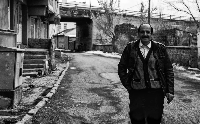 a man stands outside on the sidewalk wearing pants and a jacket