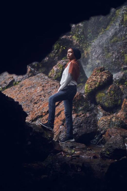 a woman poses near some rocks, taking a selfie