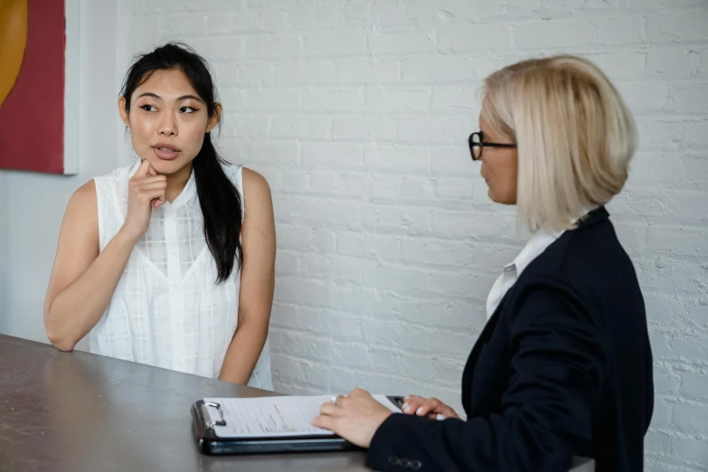 a woman in a white dress talking to another woman