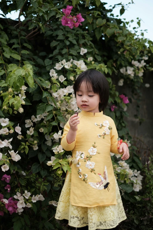 a  standing by some flowers and holding soing up