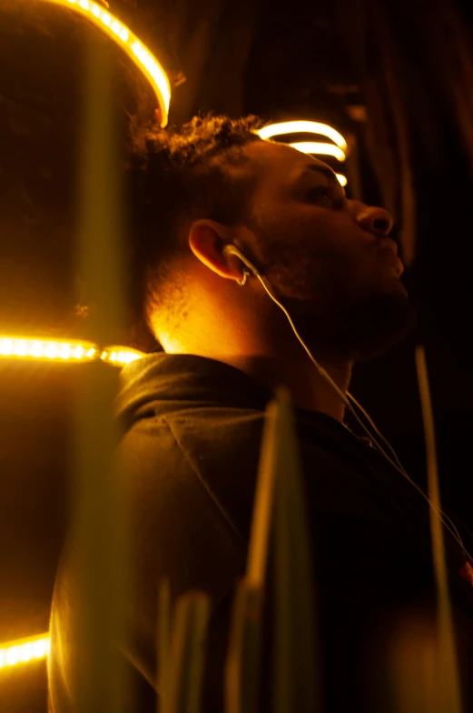 a young man wearing earphones looking up at light