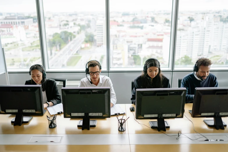 the four people are sitting at the table with their computers