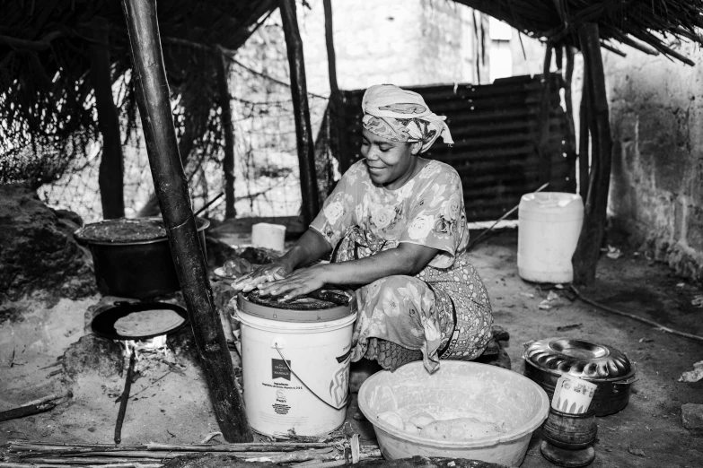 a woman is cooking food in a pot on the floor