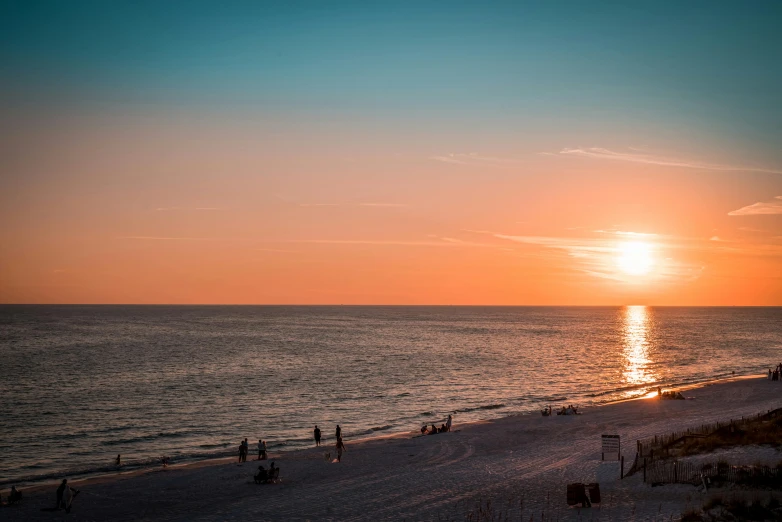 sun rising over the beach with people walking around