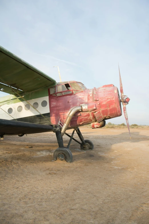 a small propeller airplane that has fallen apart in the desert