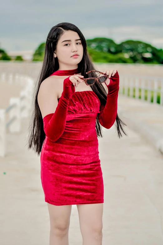 a beautiful woman standing outside in a red dress