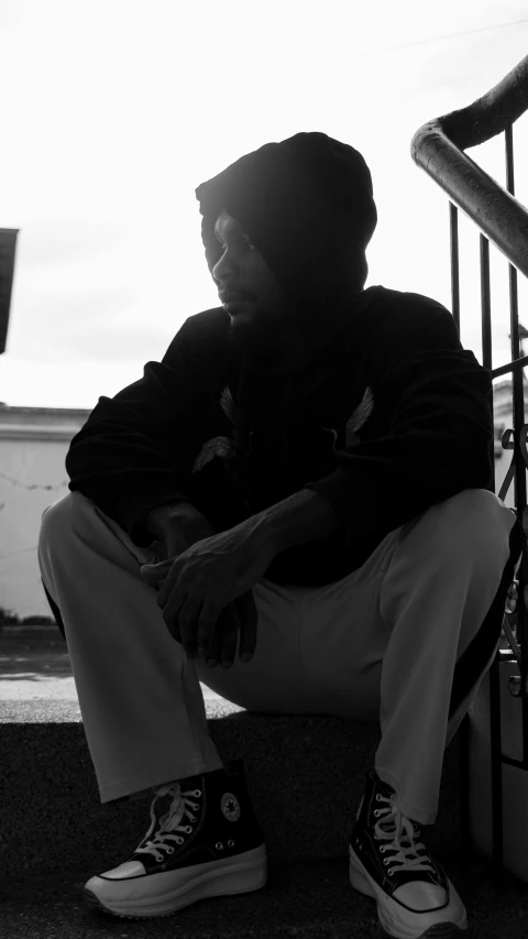 a man sitting on top of stairs in a black and white po