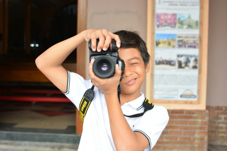 a boy takes a po while wearing a black camera