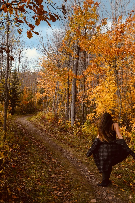 the woman is walking through the colorful autumn trees