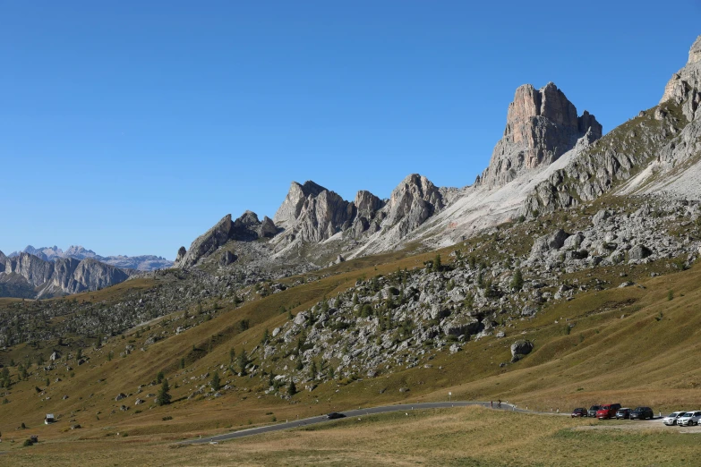 some cars parked in the grass near large mountains