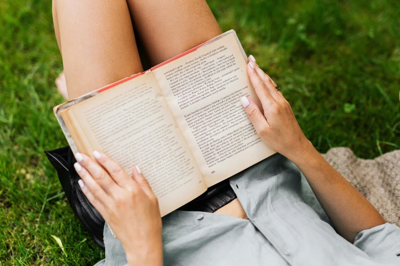 a woman laying on the ground holding an open book