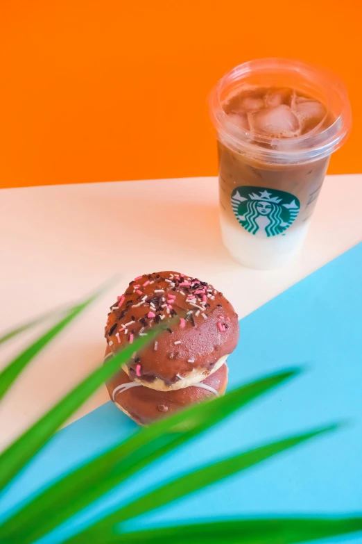 a cup of iced coffee next to two donuts