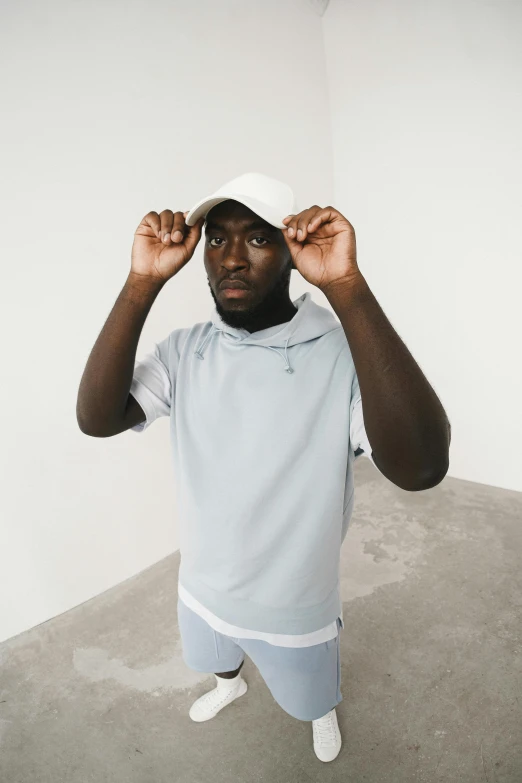 a young man is posing in his room while holding up a hat